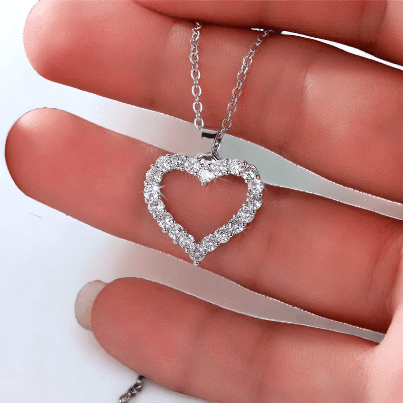 Silver heart pendant necklace with cubic zirconia diamonds  and a silver chain in someone's hand