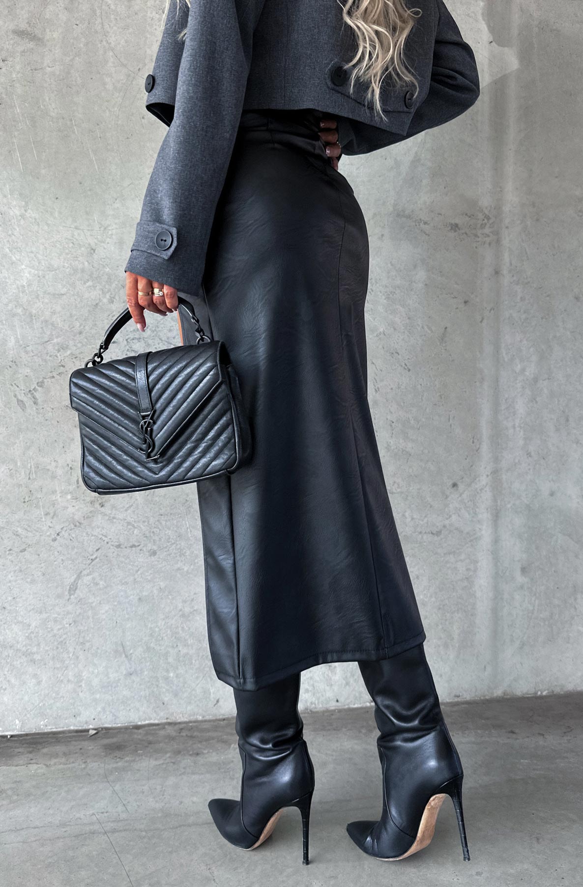 A from behind Photo of a A women wearing a black leatherette maxi skirt